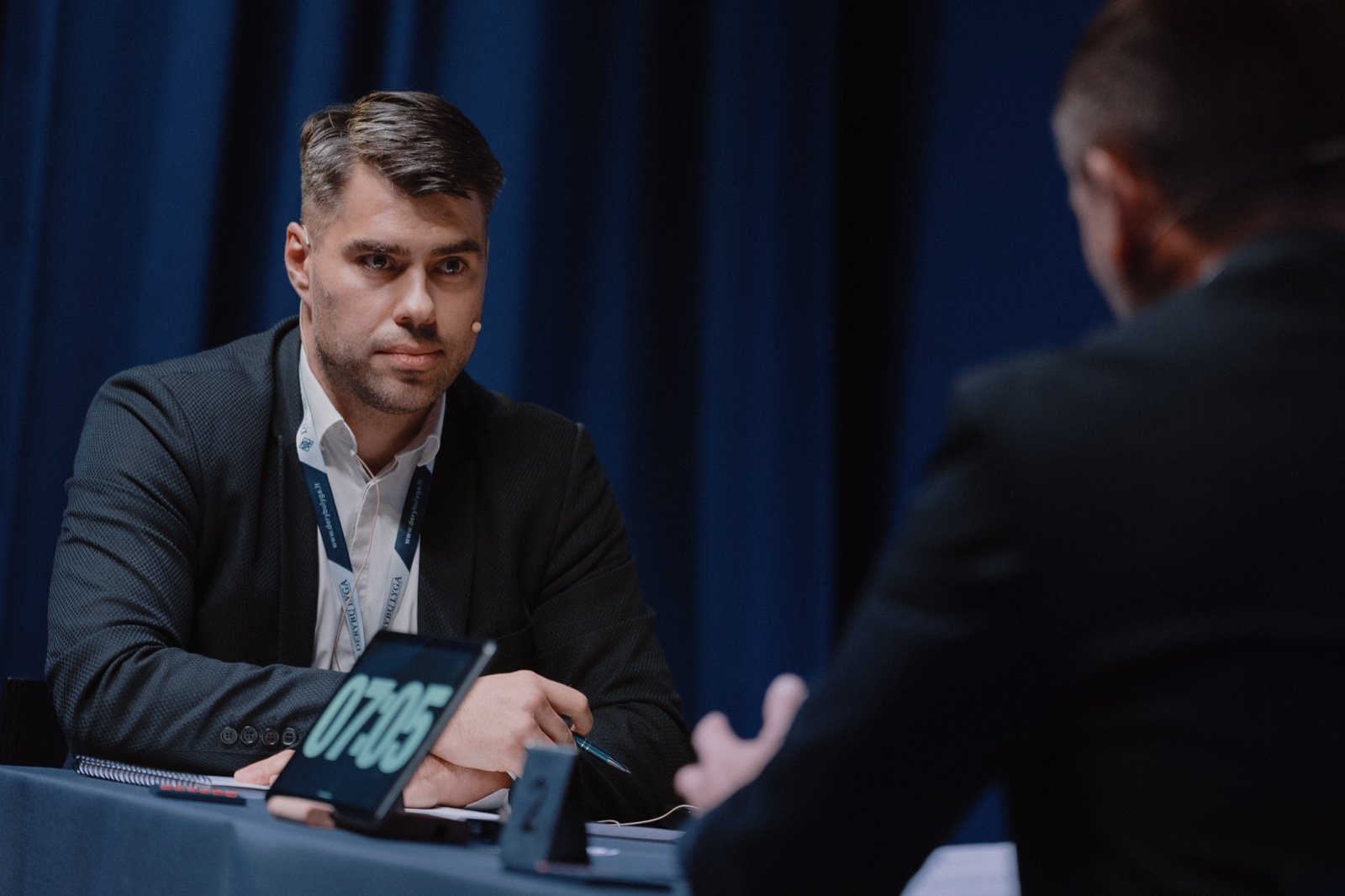 Derybininkas įsiklauso į oponento žodžius, ekrane rodomas 07:05 laikmatis